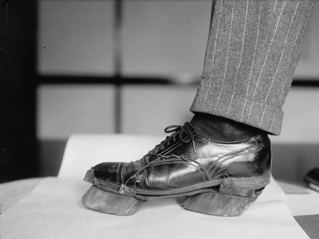 Black and white photo of a man's shoe with carved wooden cow hooves strapped to the sole, used by Prohibition-era moonshiners to disguise their footprints