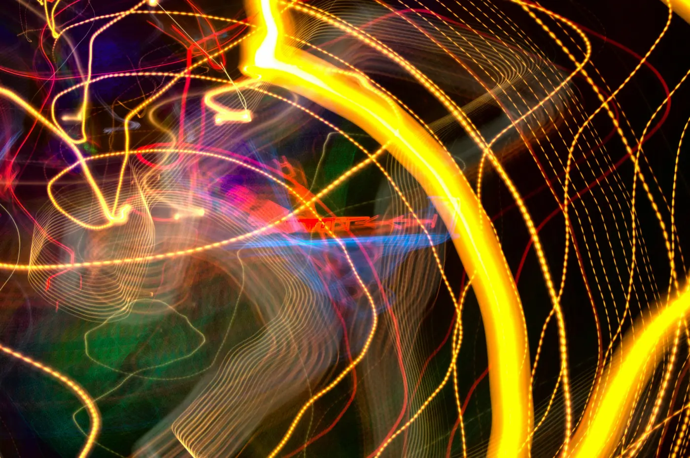 Auto-generated description: Vibrant light trails intertwine in an abstract pattern of swirling colors, including yellow, red, and blue.