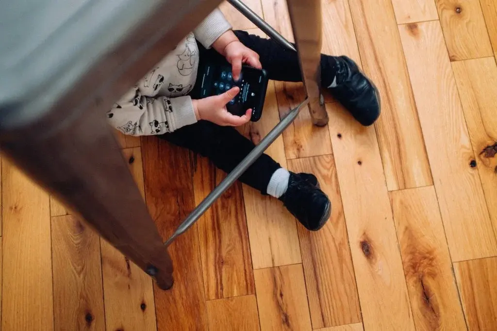 Kid under chair looking at screens