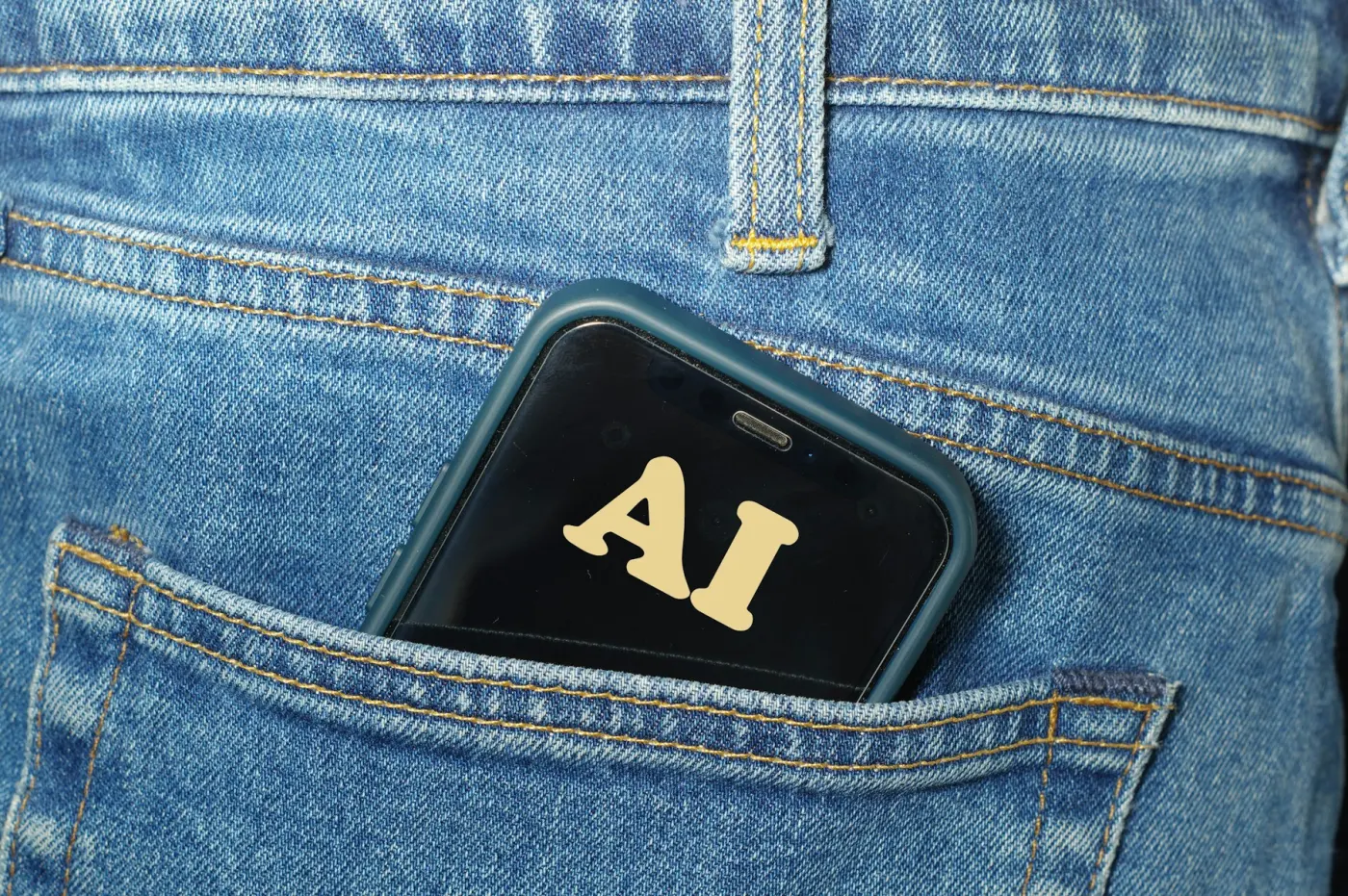A smartphone with the text AI displayed on the screen is partially tucked into the back pocket of blue jeans.