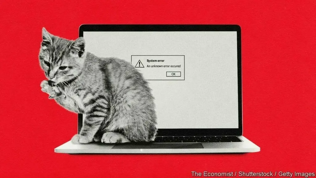 Cat next to laptop which has on-screen "System error"