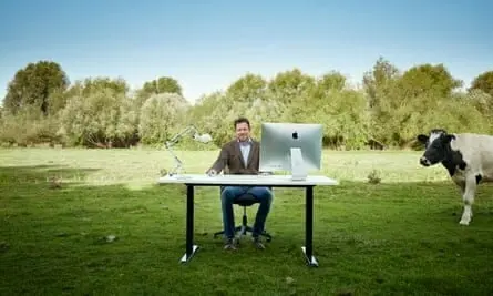 Man in field sitting at desk and computer